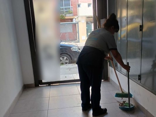 Personal de C-Planet con uniforme barriendo el hall de entrada de un edificio