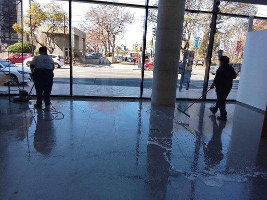 Personal de C-Planet limpiando y puliendo el piso de un local con lustradora